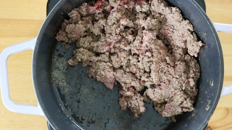 Move the meat to the side of the pot and add garlic to cook it for a minute.